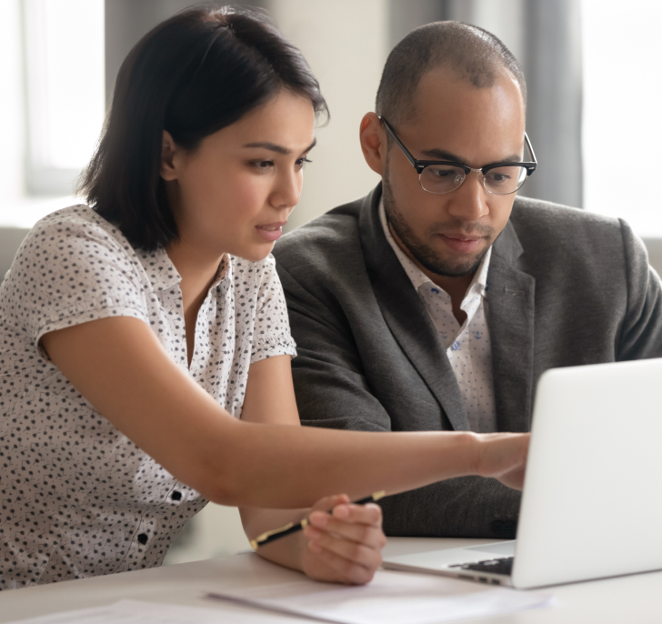 Man and woman sitting looking at laptop screen