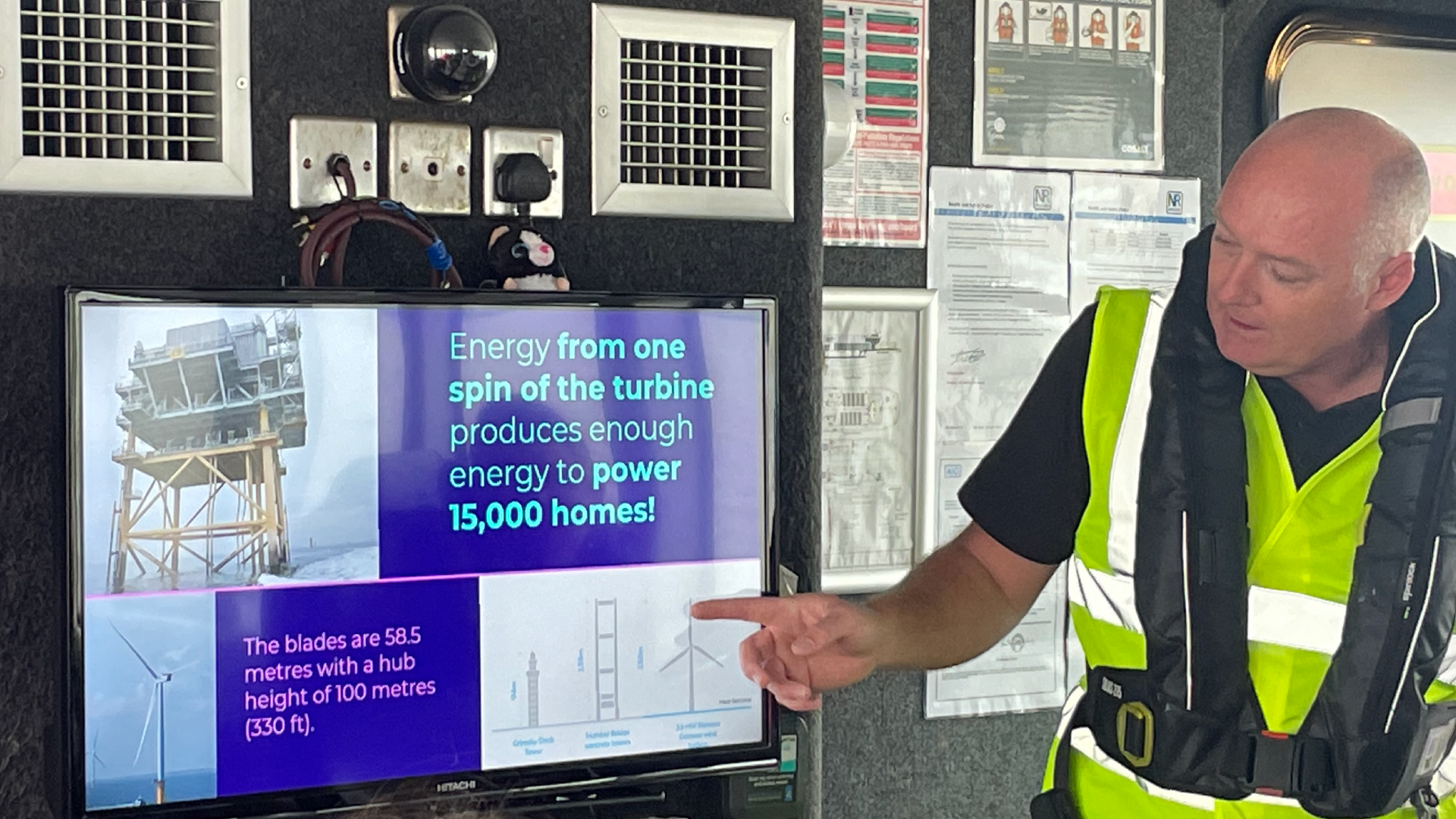 Worker at the wind farm explaining about how much energy is generated from the turbine spins