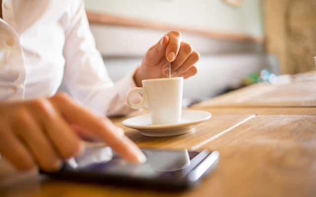 Person typing on mobile with coffee