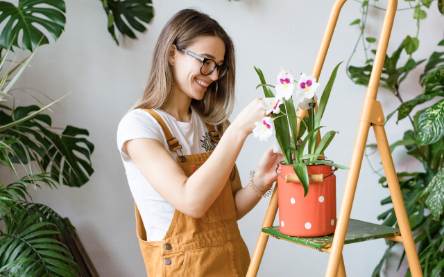 Woman in orange dungarees planting an orchid