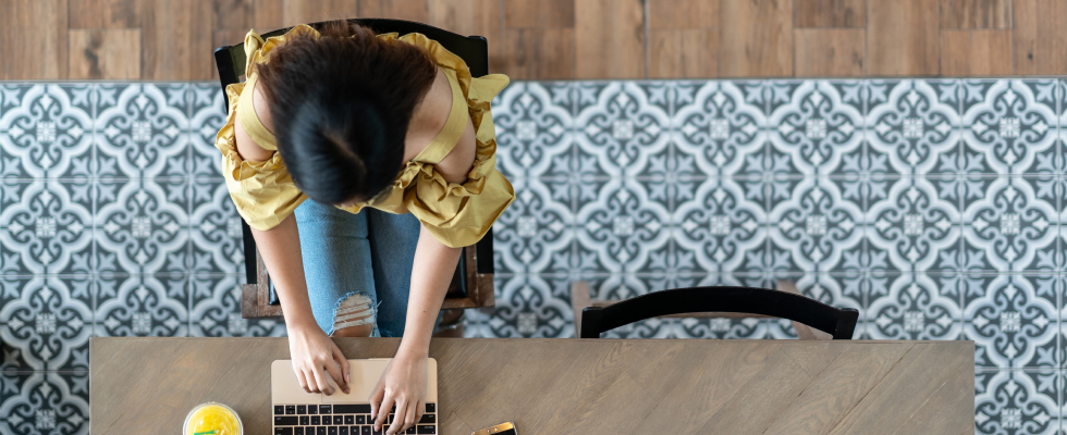 Top view of woman at desk typing on laptop