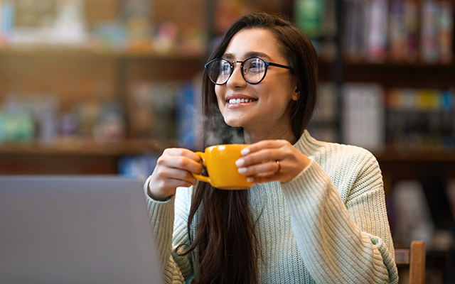 Young woman drinking tea or coffee from orange cup