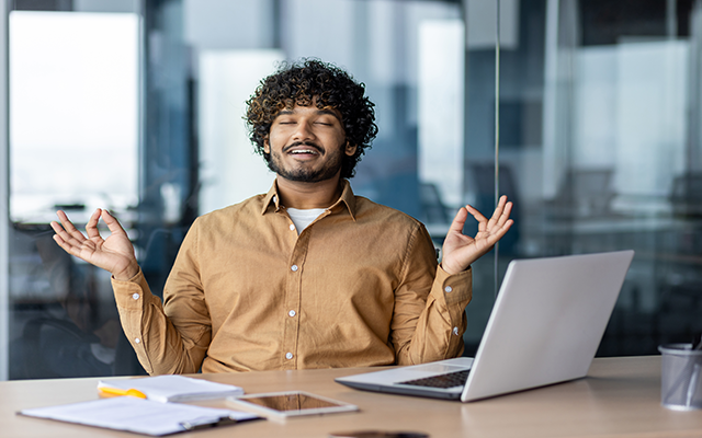 Smiling man in yoga pose at laptop