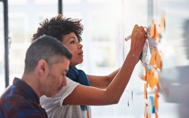 Man and woman at whiteboard with post-it notes