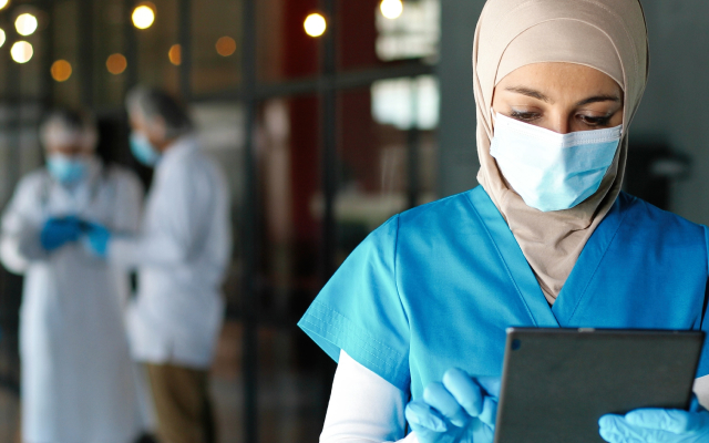 Nurse wearing facemask looking at tablet