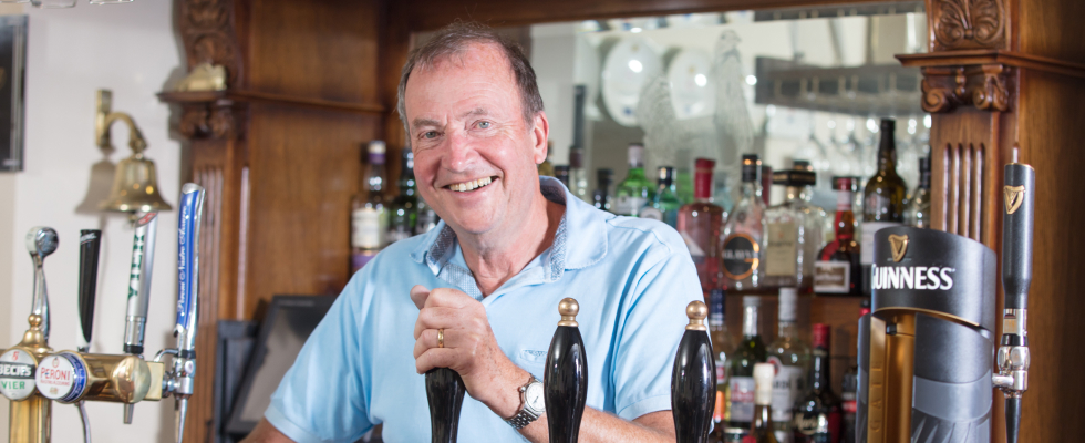 man pulling pint while smiling at camera