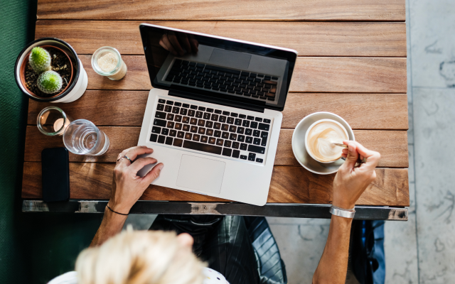 Bird's-eye view of person with coffee working on laptop