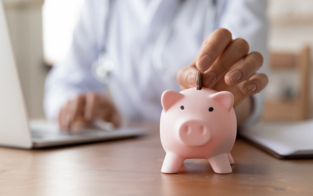 Person on laptop putting coin into piggy bank