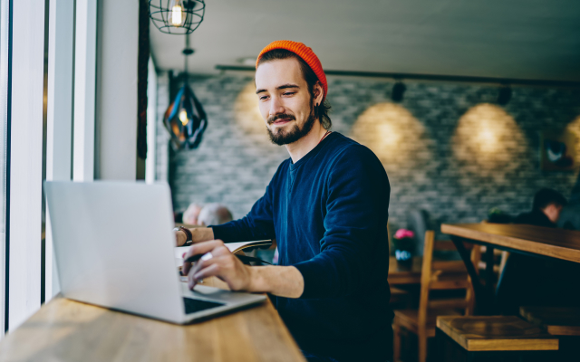 Man sitting at table looking at laptop