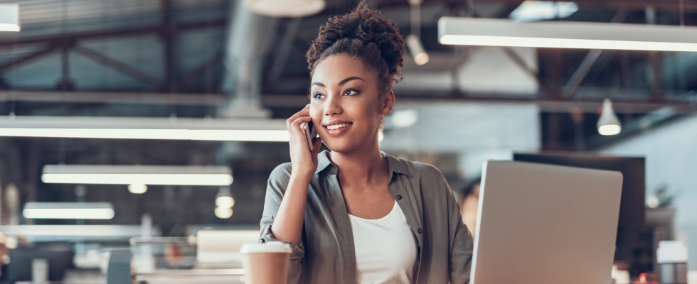 woman talking on phone and working at laptop smiling