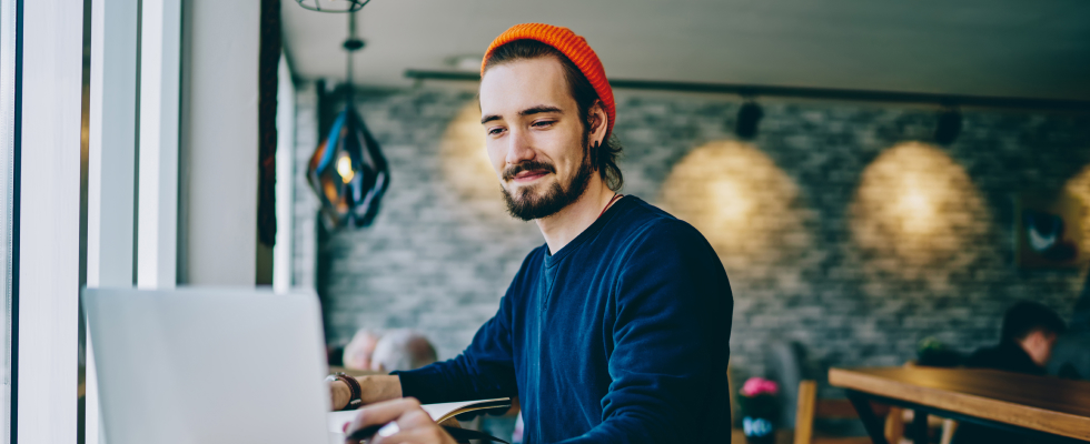 Man sitting at a table typing on laptop