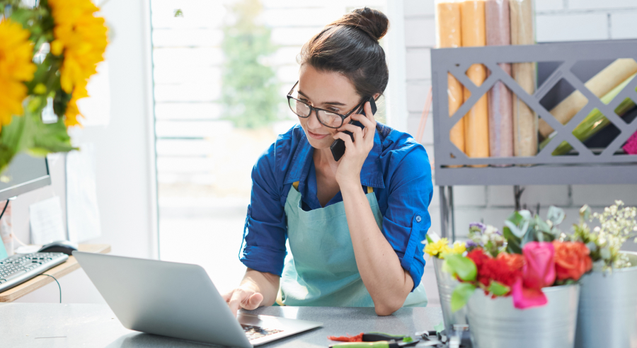 Woman sitting down on the phone, looking at laptop