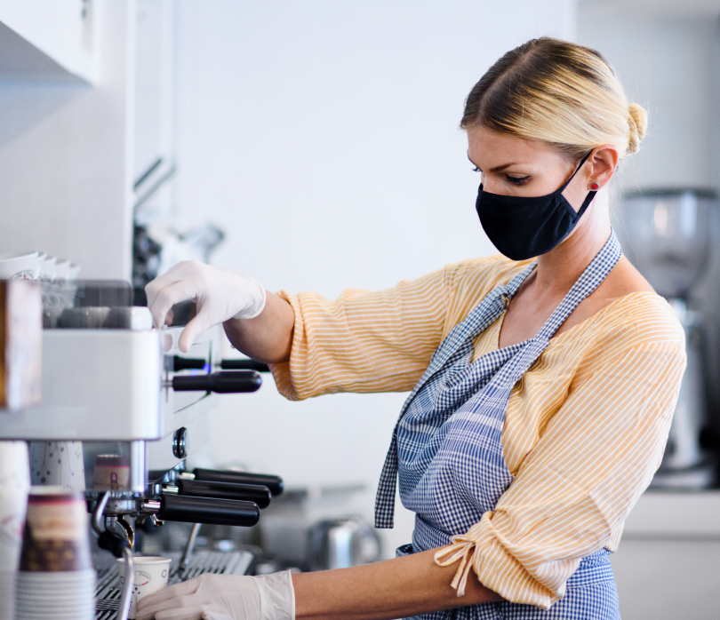 Woman at the coffee machine with a mask on