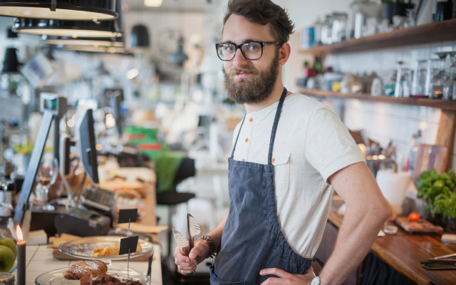 Man standing behind counter, at a coffee shop