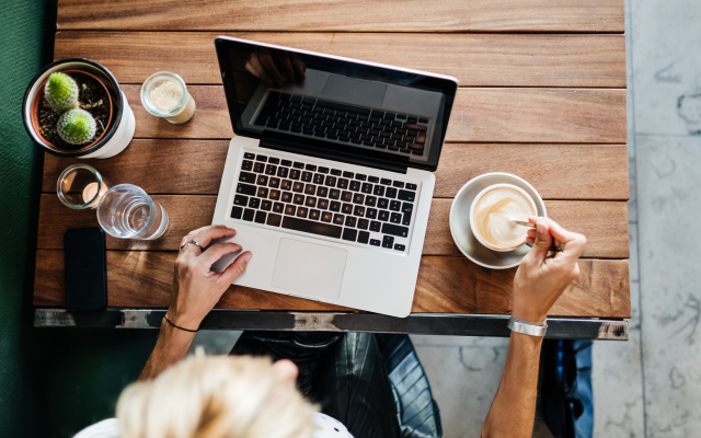 Bird's-eye view of person working on laptop with coffee