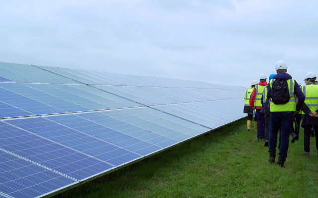 Group of people walking next to solar panels