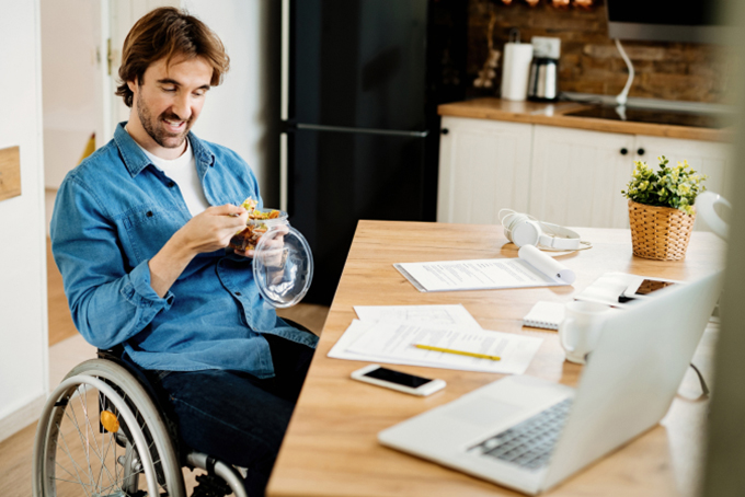 Man in wheelchair sitting at desk eating