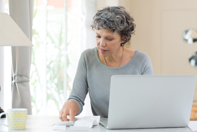 Woman sitting at desk, and looking at receipts