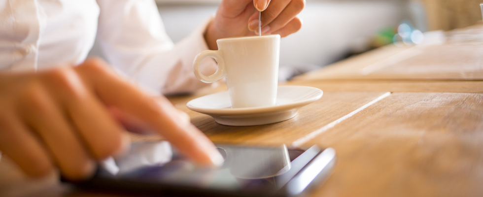 Person typing on mobile with cup of coffee