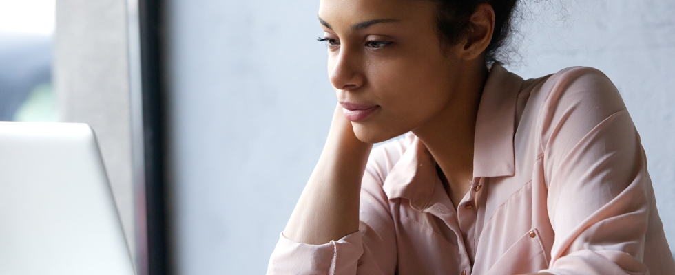 Young woman sitting down, looking at laptop